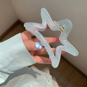 Close-up of translucent mint blue star-shaped hair claw clip with metal spring