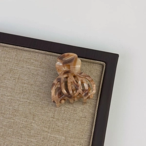 Detail of tortoiseshell acetate hair claw clip showing polished texture and metal spring