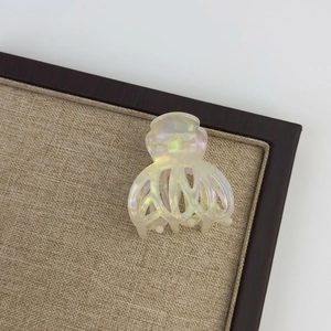 Detail shot of pearlescent acetate hair claw clip with iridescent finish on wooden display