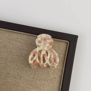 Detailed top view of a marble pattern acetate hair claw clip on a linen display board