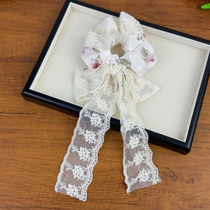 French lace floral scrunchie with detachable bow streamer on wooden display tray