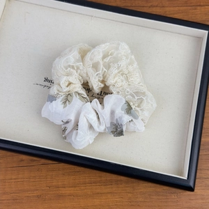 Detail of floral lace scrunchie with grey-green leaf pattern on elegant white tray