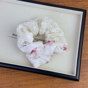 Macro detail of French style lace scrunchie with pink cherry blossom floral pattern