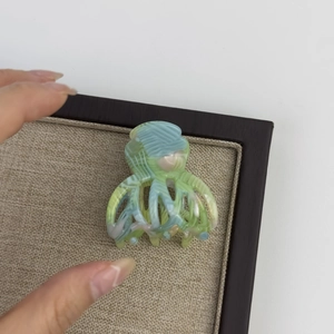 Detail of medium acetate hair claw with green marble texture on burlap display mat