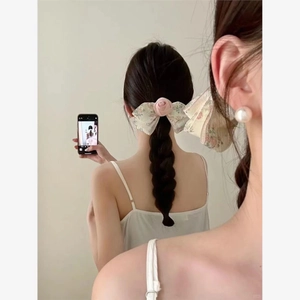 Elegant floral ribbon hair clip with pink rose and pearl earrings on a model