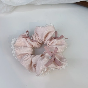 Dettaglio di elastico in seta rosa con pizzo bianco, fiocchi di raso e perle decorative