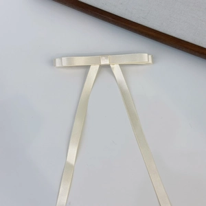 Close-up of cream off-white satin ribbon bow hair clip with elegant long tail design