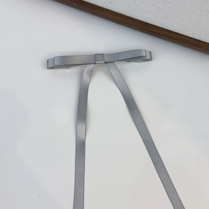 Detailed view of a grey satin bow hair clip with long flowing ribbons and silky texture
