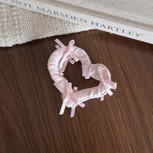 Détail d'une pince à cheveux cœur en satin rose avec nœuds sur fond de style de vie
