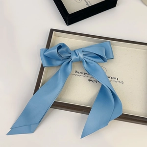 Detail of light blue satin ribbon hair clip with elegant double bow and long streamers