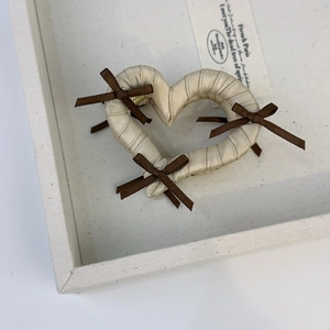 Close-up of heart-shaped hair claw with beige ribbon wrapping and small brown bows