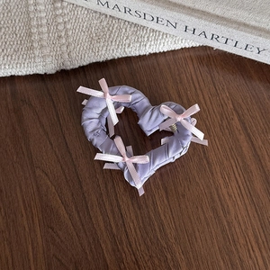 Vue détaillée d'une pince à cheveux en forme de cœur avec tissu violet et nœuds rose