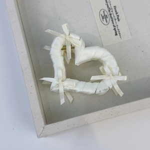 Detail of a white satin-wrapped heart hair claw with delicate bows in French style
