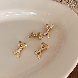 Set mit vier goldenen Metall-Schleifen-Haarspangen auf einer Keramikschale präsentiert