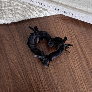 Détail d'une pince à cheveux noire en forme de cœur avec des nœuds sur un livre