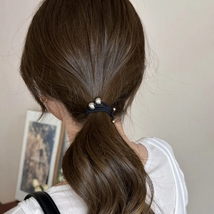 Detailed view of black elastic hair tie with asymmetrical silver metal beads on a low ponytail