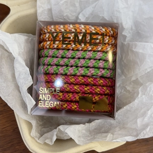 Close-up of colorful braided elastic hair ties in a premium transparent gift packaging