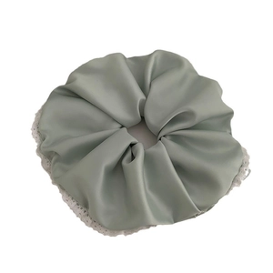 Chouchou élégant en satin vert sauge avec bordure en dentelle blanche sur fond blanc