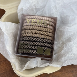 Close-up of brown elastic hair bands in a transparent box with gold text
