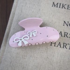 Détail de la pince à cheveux rose avec nœuds 3D blancs et strass scintillants