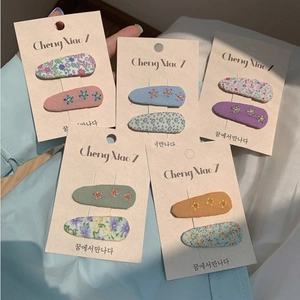Detail of floral embroidery and printed pattern on fabric snap hair clips set