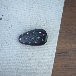 Gros plan sur la barrette noire en forme de goutte avec pois colorés et texture de cuir