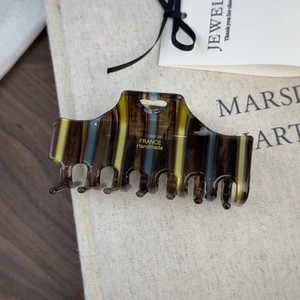 Macro view of striped acetate hair claw clip with golden France Handmade engraving