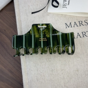 Macro view of dark green striped acetate hair claw with heart cutout and gold lettering