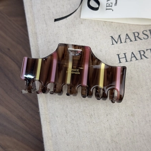 Close-up of a large striped acetate claw clip with a wood grain texture and gold lettering
