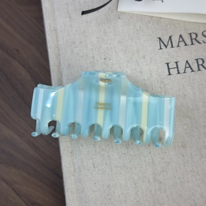 Detail of striped acetate hair claw clip showing France Handmade text on cream blue resin