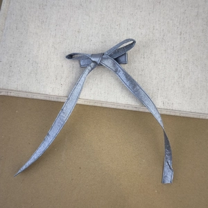 Dettaglio del fiocco in raso grigio con code lunghe e consistenza setosa