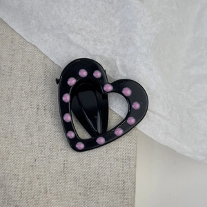 Detail view of the black heart-shaped hair clip with elegant pink polka dot enamel finish