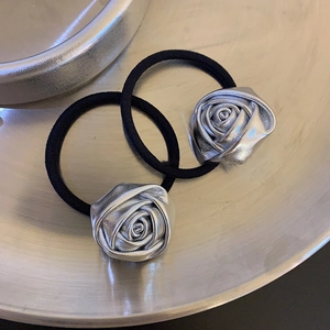 Detail von silbernen Rosen-Haargummis mit elastischen Seilen auf einem Metalltablett