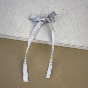 Dettaglio del fermaglio per capelli a fiocco argento metallizzato con nastri lunghi