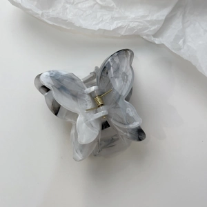 Macro view of grey marble texture butterfly hair claw clip with golden spring mechanism