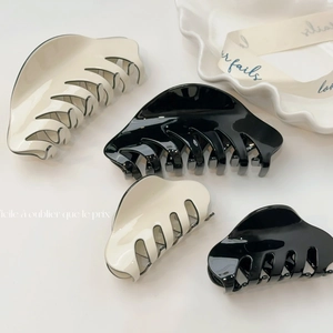 Pinces à cheveux françaises classiques en acétate noir et crème sur plateau décoratif