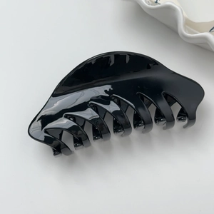 Détail de la pince à cheveux en acétate noir brillant au fini lisse et design incurvé