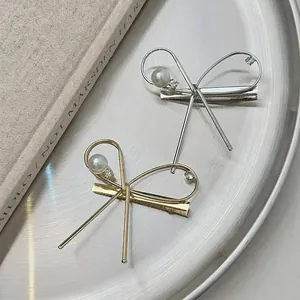 Pince à cheveux nœud asymétrique avec perles et strass en finitions dorée et argentée