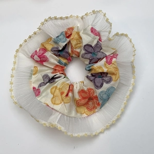 Floral print scrunchie with white lace trim and yellow embroidery on white background