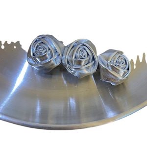 Drei silberne Leder-Rosen-Haarspangen auf Metallständer im eleganten minimalistischen Stil