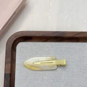 Dettaglio di un fermaglio per capelli in resina giallo crema con texture marmorizzata