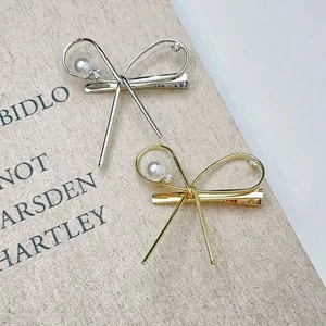 Barrettes à nœuds minimalistes dorées et argentées avec perles et strass sur un livre