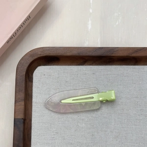Dettaglio di un fermaglio per capelli verde marmo su vassoio in legno con libro decorativo