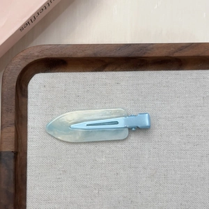 Fermaglio per capelli in resina marmorizzata blu con glitter su vassoio in lino