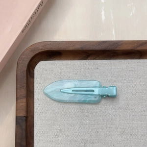 Dettaglio della molletta per capelli marmorizzata azzurra con glitter e clip in metallo