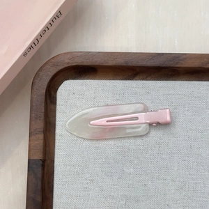 Dettaglio di un fermaglio per capelli in resina rosa marmorizzata con glitter su vassoio