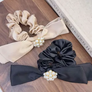 Detailed view of pearl and rhinestone floral accent on elegant satin ribbon hair tie