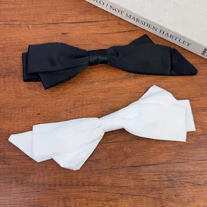Elegant black and white satin bow hair clips in French style on a vintage wooden desk
