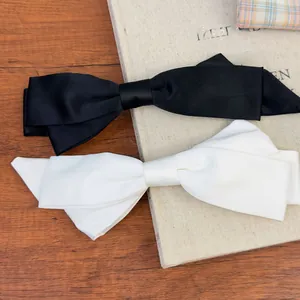 Detailed close-up of premium black and white satin bow hair clips on a wooden surface