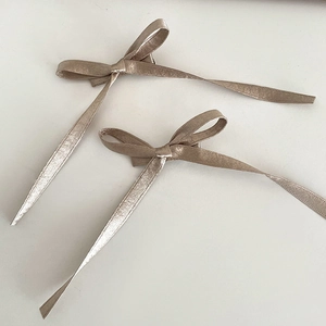 Détail montrant deux nœuds papillon en satin champagne avec de longs rubans élégants